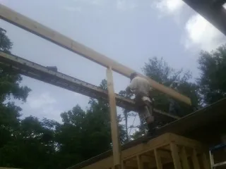Carpenter setting a ridge beam over a new addition frame — Ice Dam Removal by Roofing Brothers in East Leroy