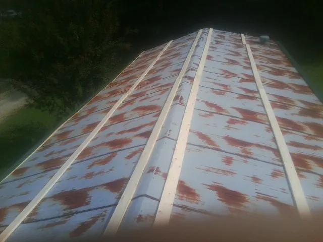 Rusted metal roof panels with new wood purlins before replacement — Storm Damage Roof Repair in East Leroy by Roofing Brothers