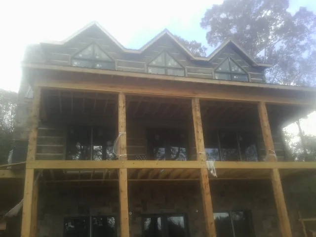 Dormers and porch framing on a large log home under construction — Roof Coating work by our crew in East Leroy