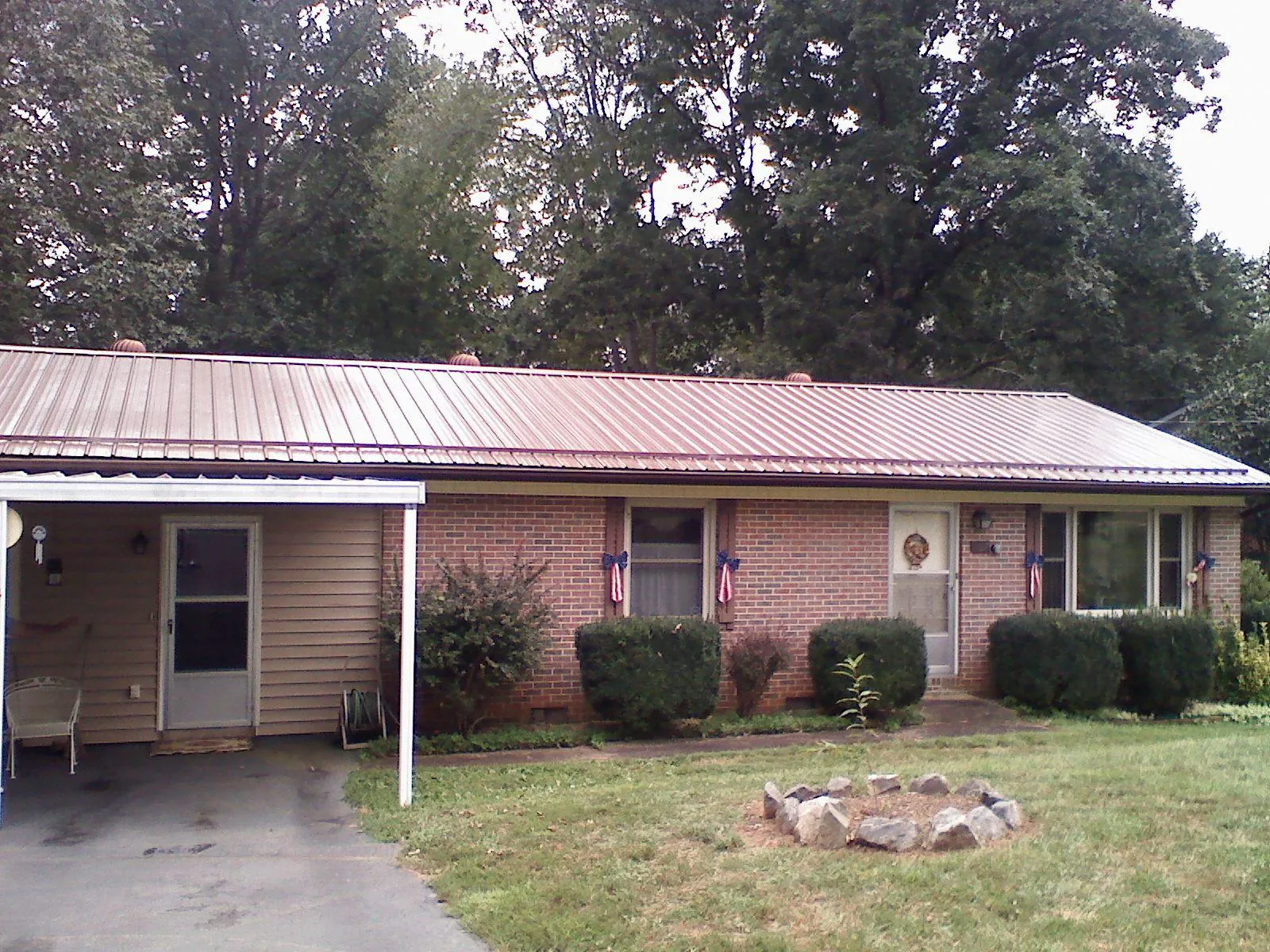 Bronze metal roof and carport on a brick ranch home — Roof Repair work by our crew in East Leroy