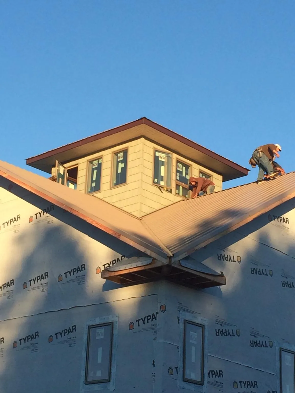 Roofers working around a rooftop cupola on a new metal roof at sunset — Roof Waterproofing in East Leroy by Roofing Brothers